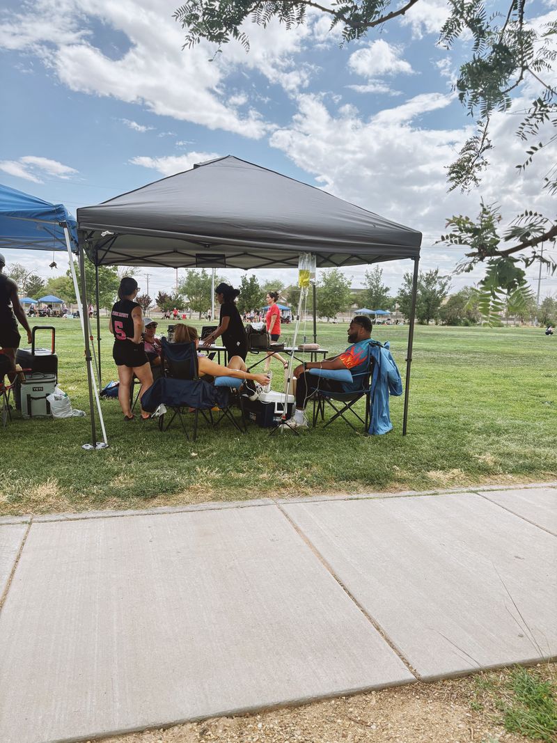 Clients relaxing with IV drips under the Flowstate tent at a kickball tournament